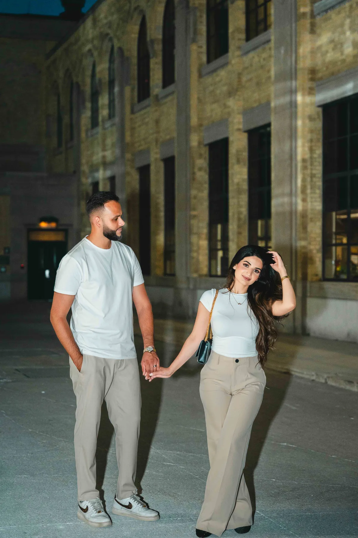 The couple holding hands outside a city building at A and F’s couples session.