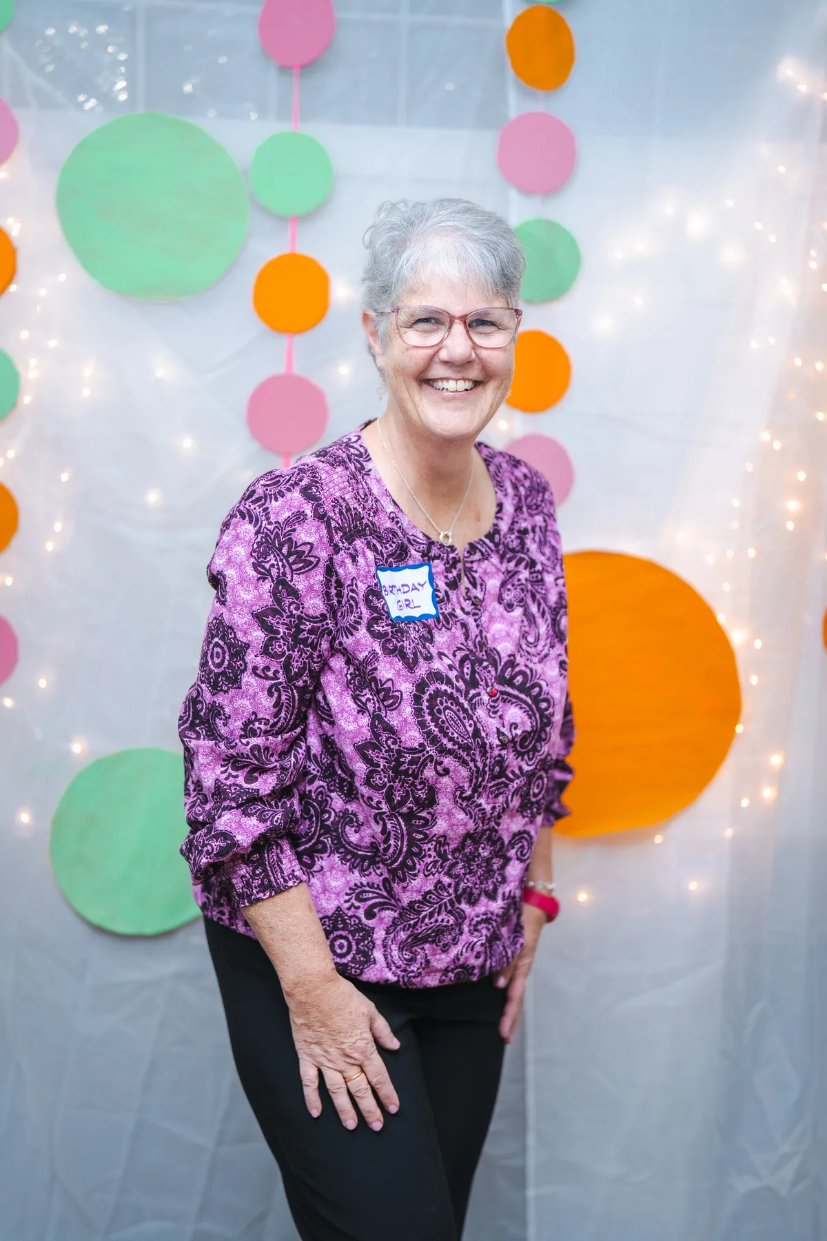 A woman posing in a purple floral outfit at Alison’s birthday celebration.