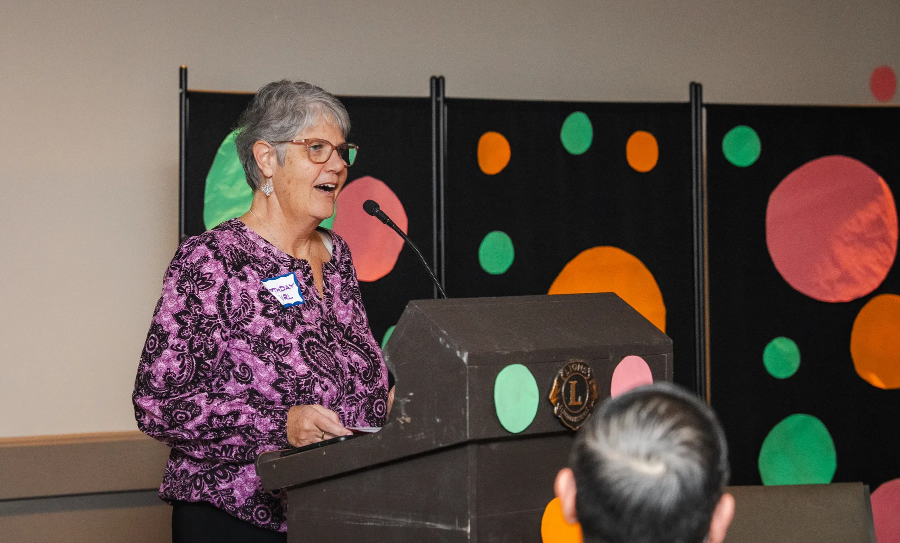 A woman speaking at the lectern at Alison’s birthday celebration.