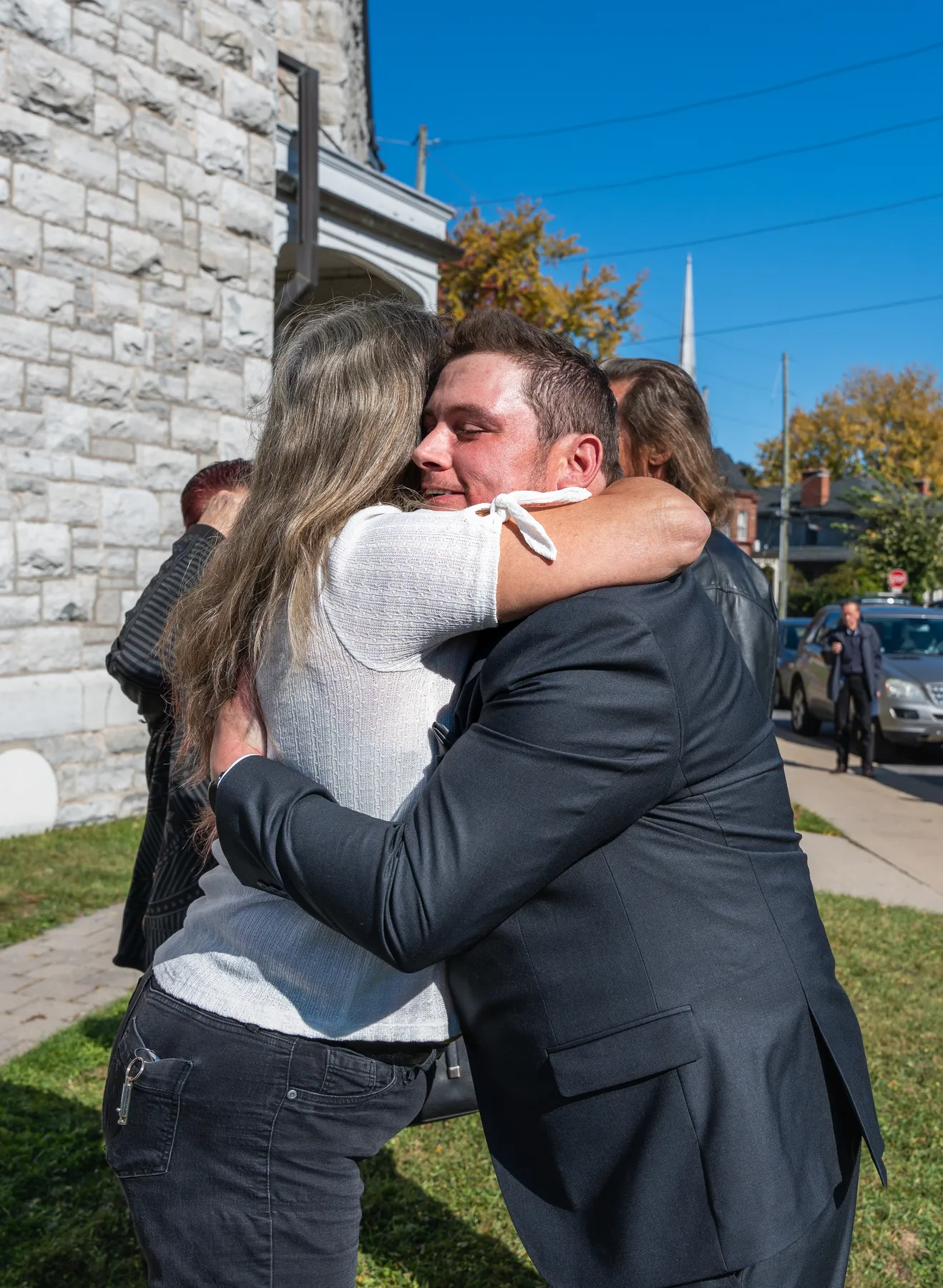 Guests hugging outside the church at Kody and Jaz’s wedding.