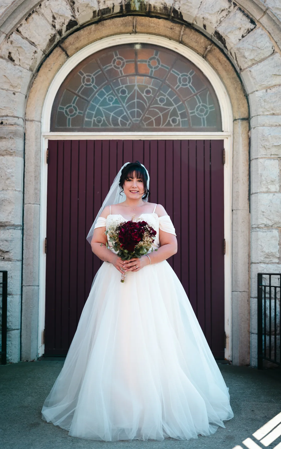 The bride posing at the red church door at Kody and Jaz’s wedding.