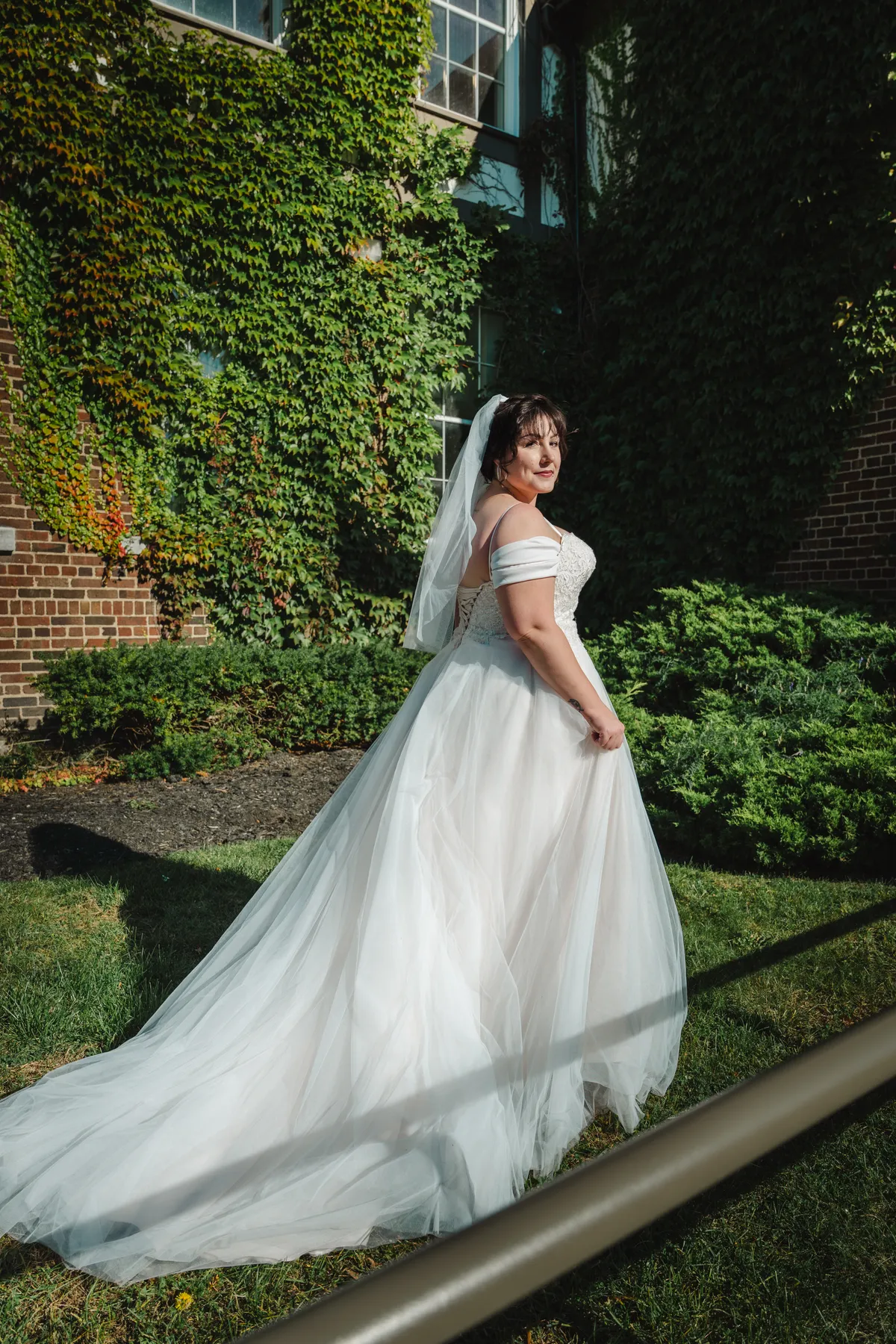 The bride posing in a garden with her gown trailing behind at Kody and Jaz’s wedding.