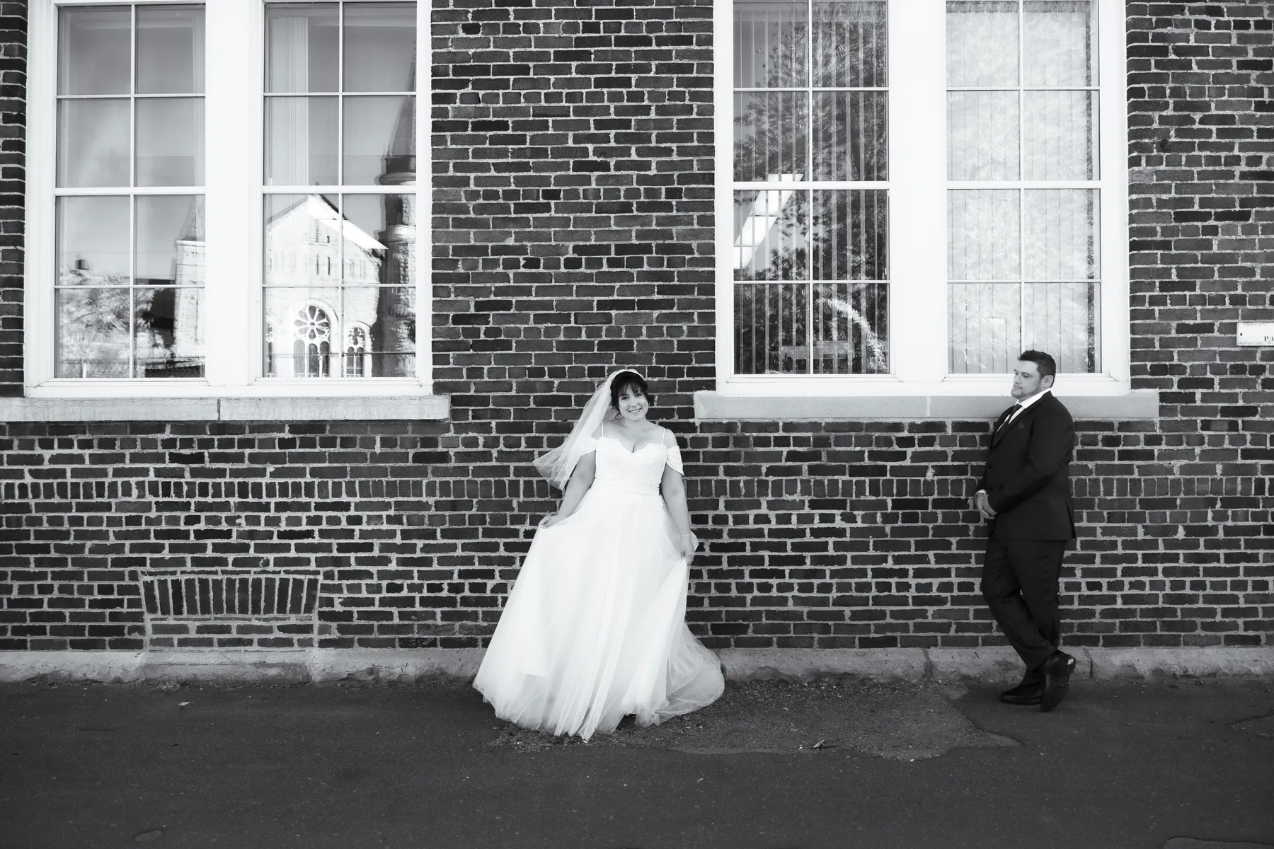 The couple walking and posing beside a brick wall at Kody and Jaz’s wedding.