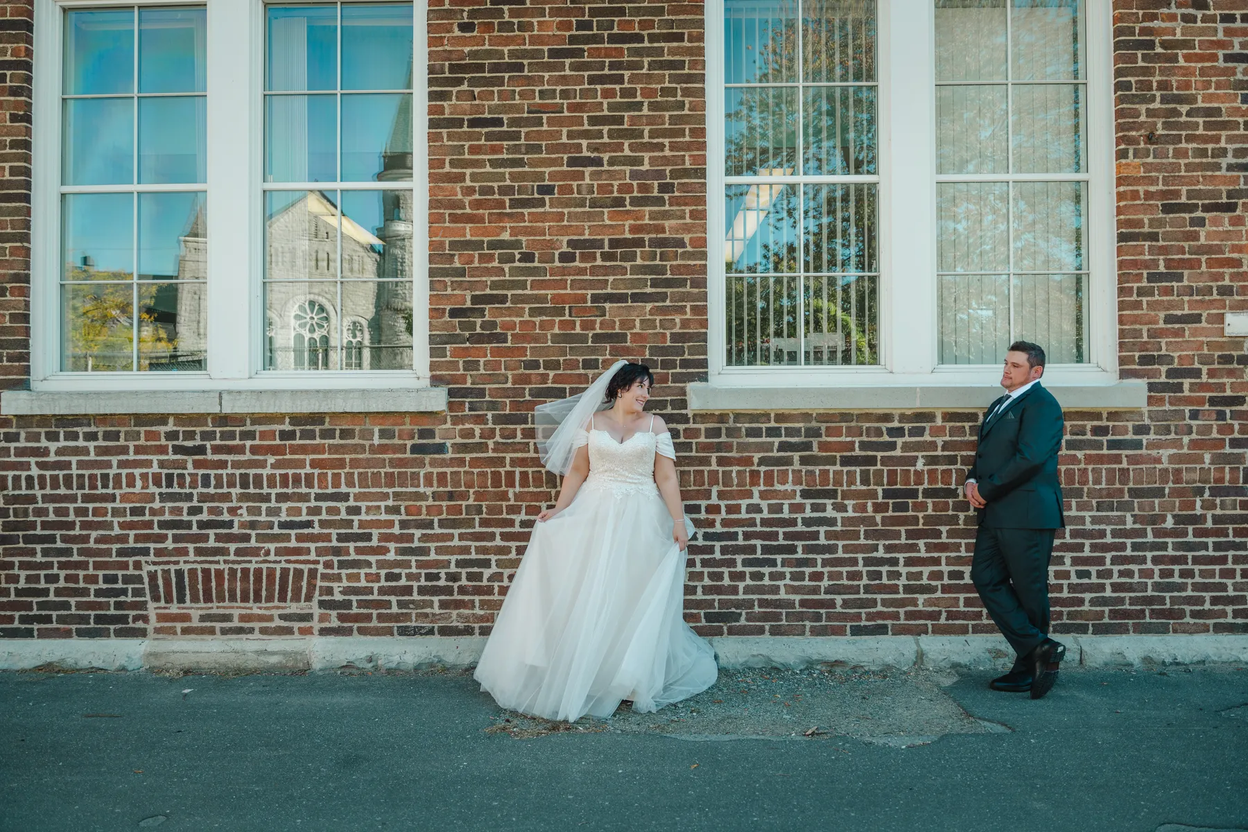 The couple walking and posing beside a brick wall at Kody and Jaz’s wedding.