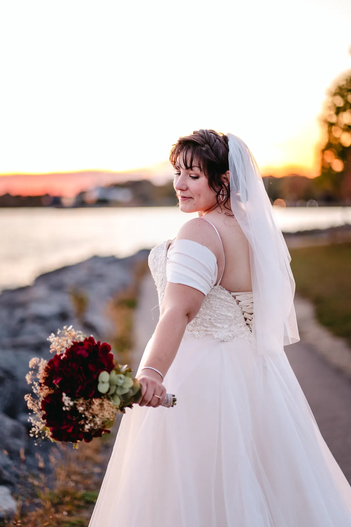 The bride posing by the water at sunset at Kody and Jaz’s wedding.