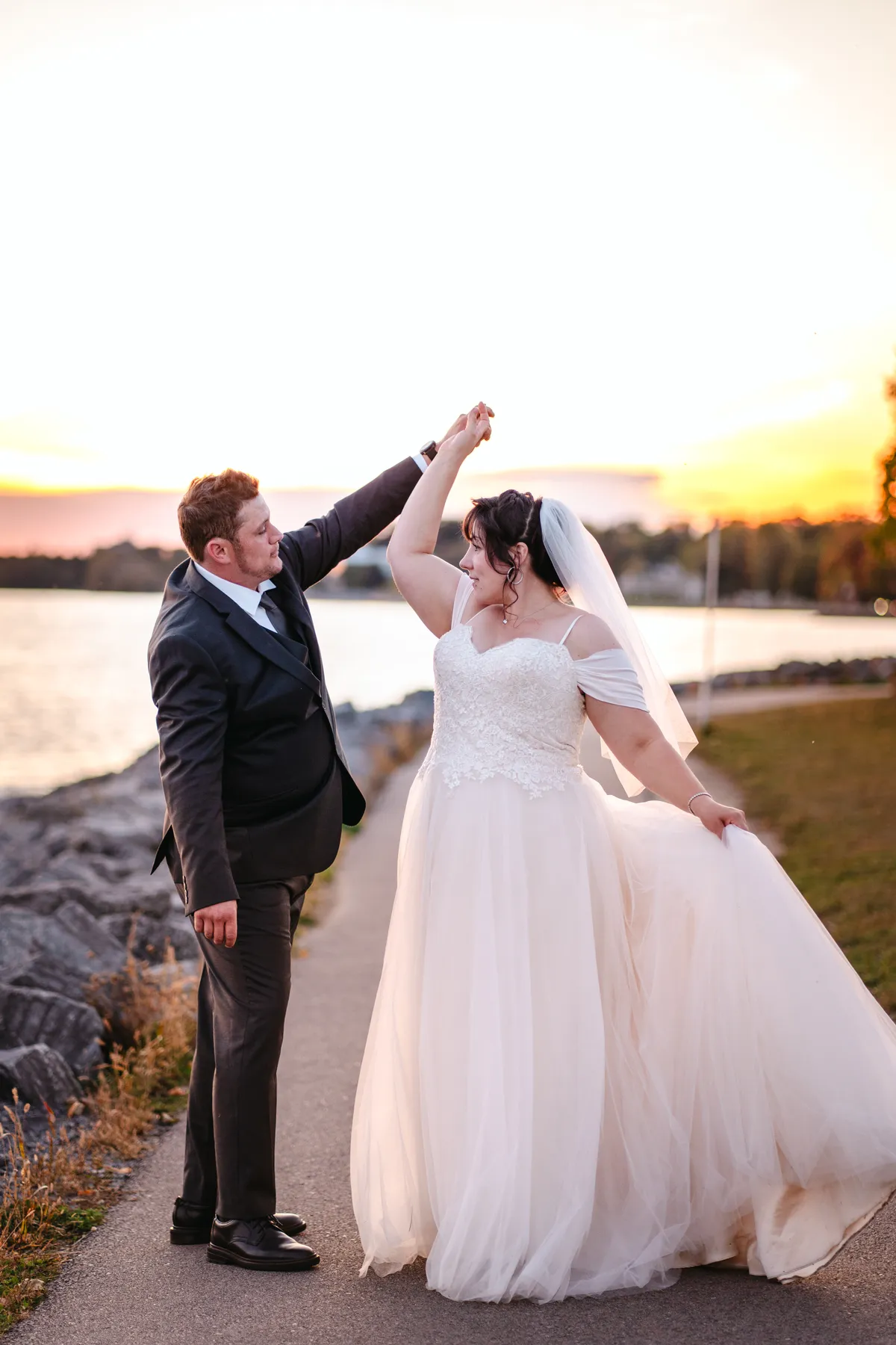 The couple walking and posing by the water at sunset at Kody and Jaz’s wedding.