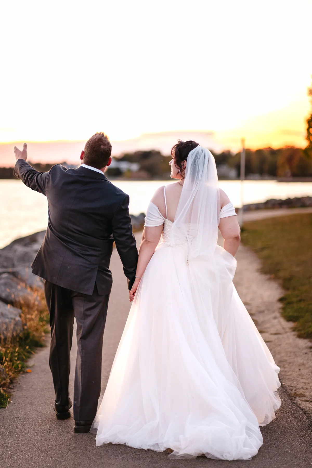 The couple walking and posing by the water at sunset at Kody and Jaz’s wedding.