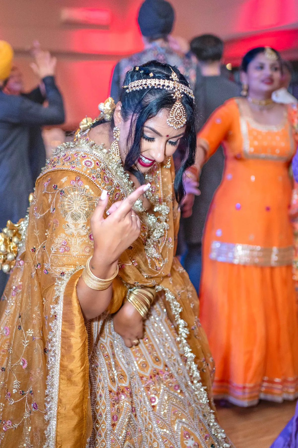 A woman dancing in a gold outfit at Jessie and Erin’s Haldi celebration.