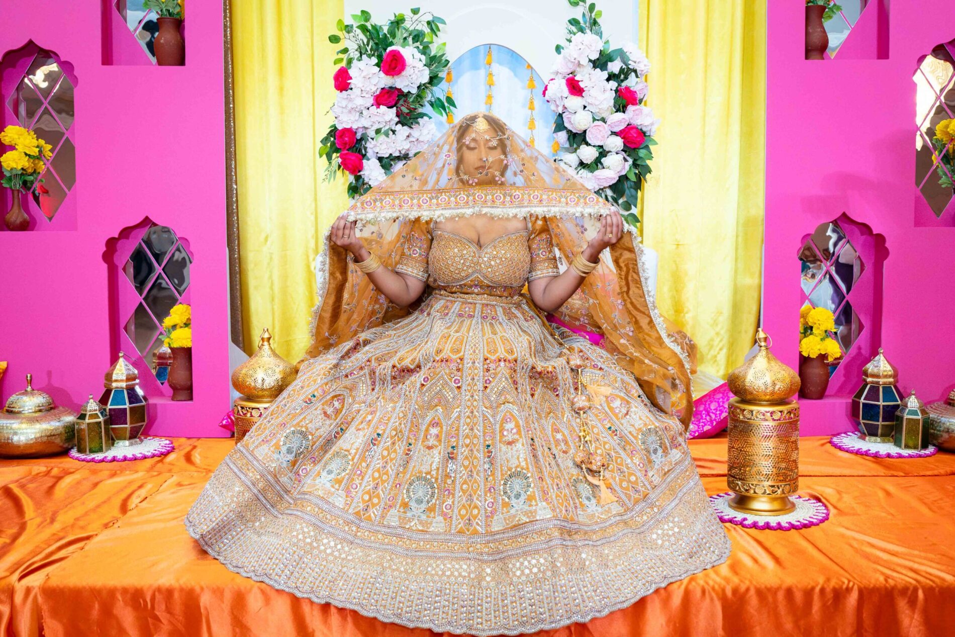 Jessie in orange lehenga with veil poses serenely at her Haldi ceremony in Winnipeg, 2024.