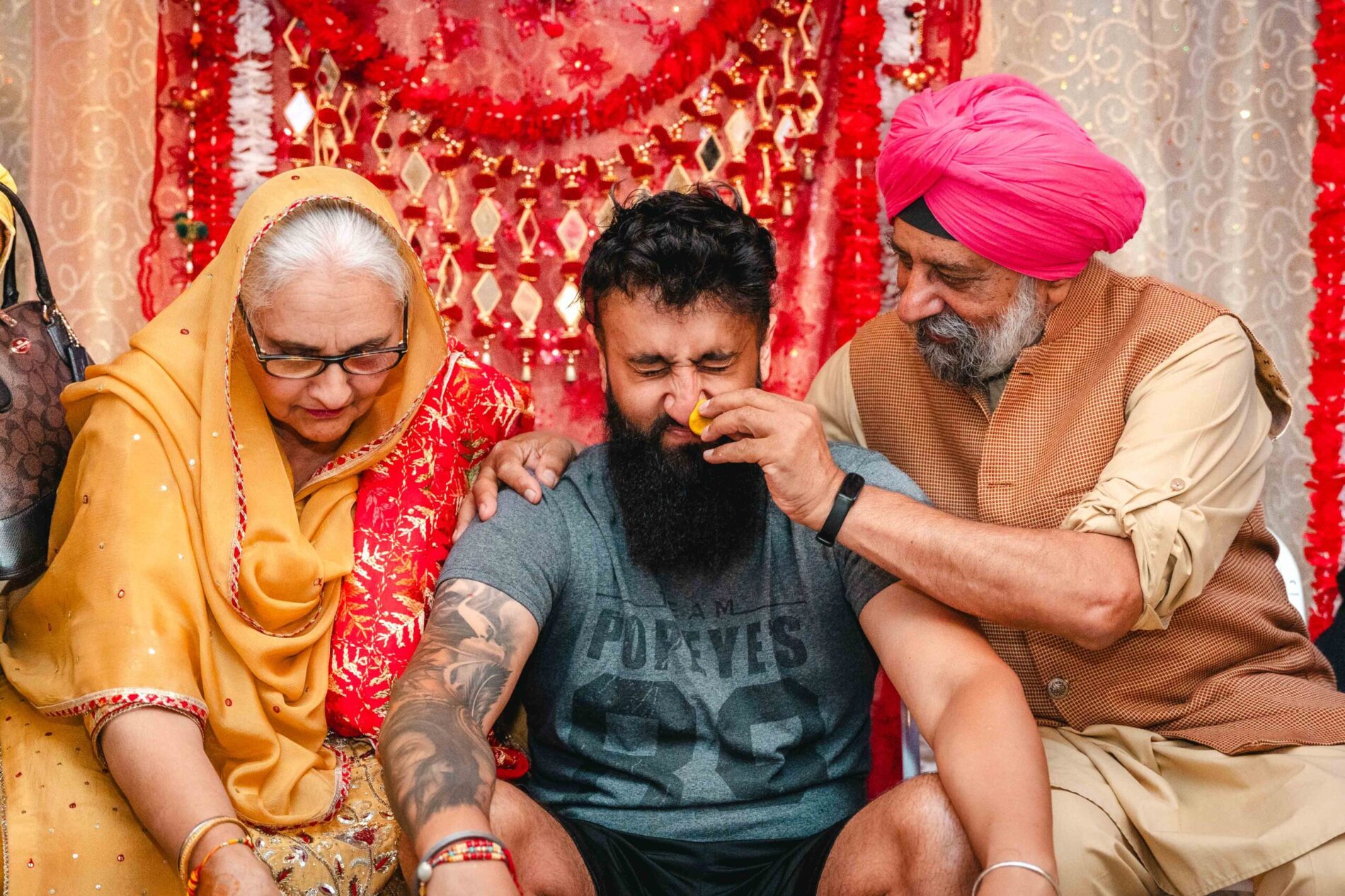 Aaron receives blessing from parents at his 2024 Haldi ceremony with vibrant decor.